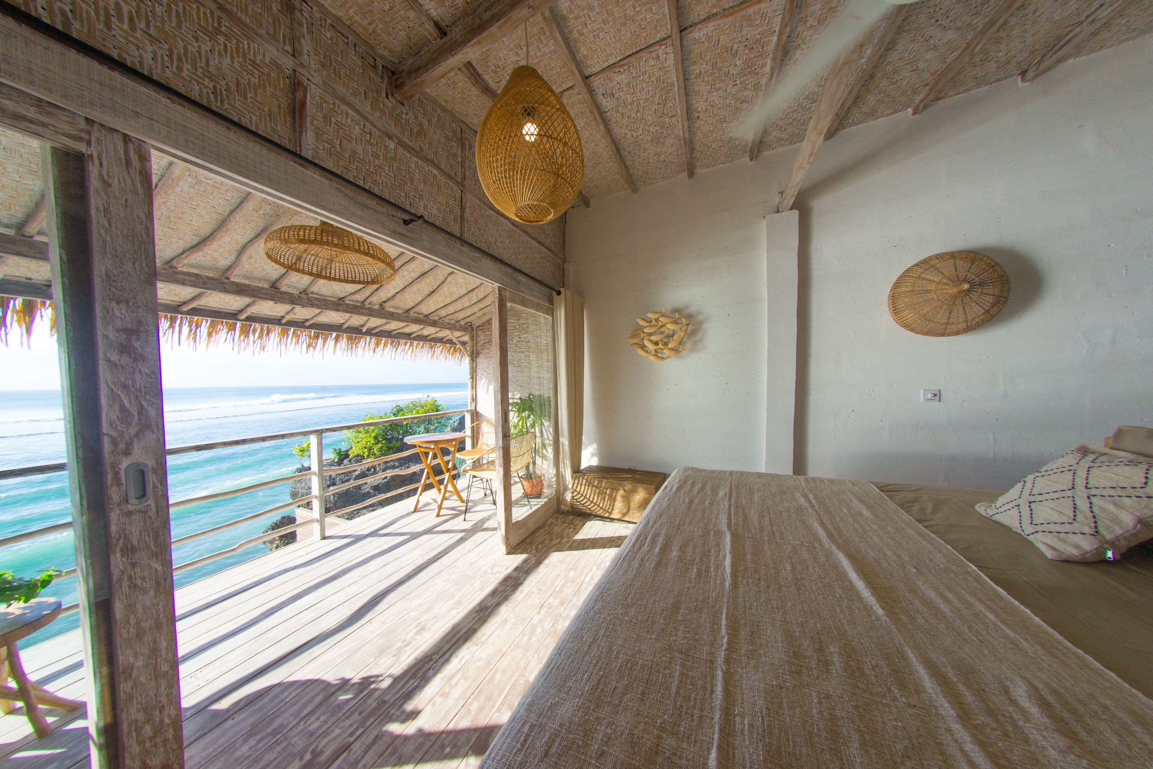 A room with a bed, a table, and a view of the ocean.