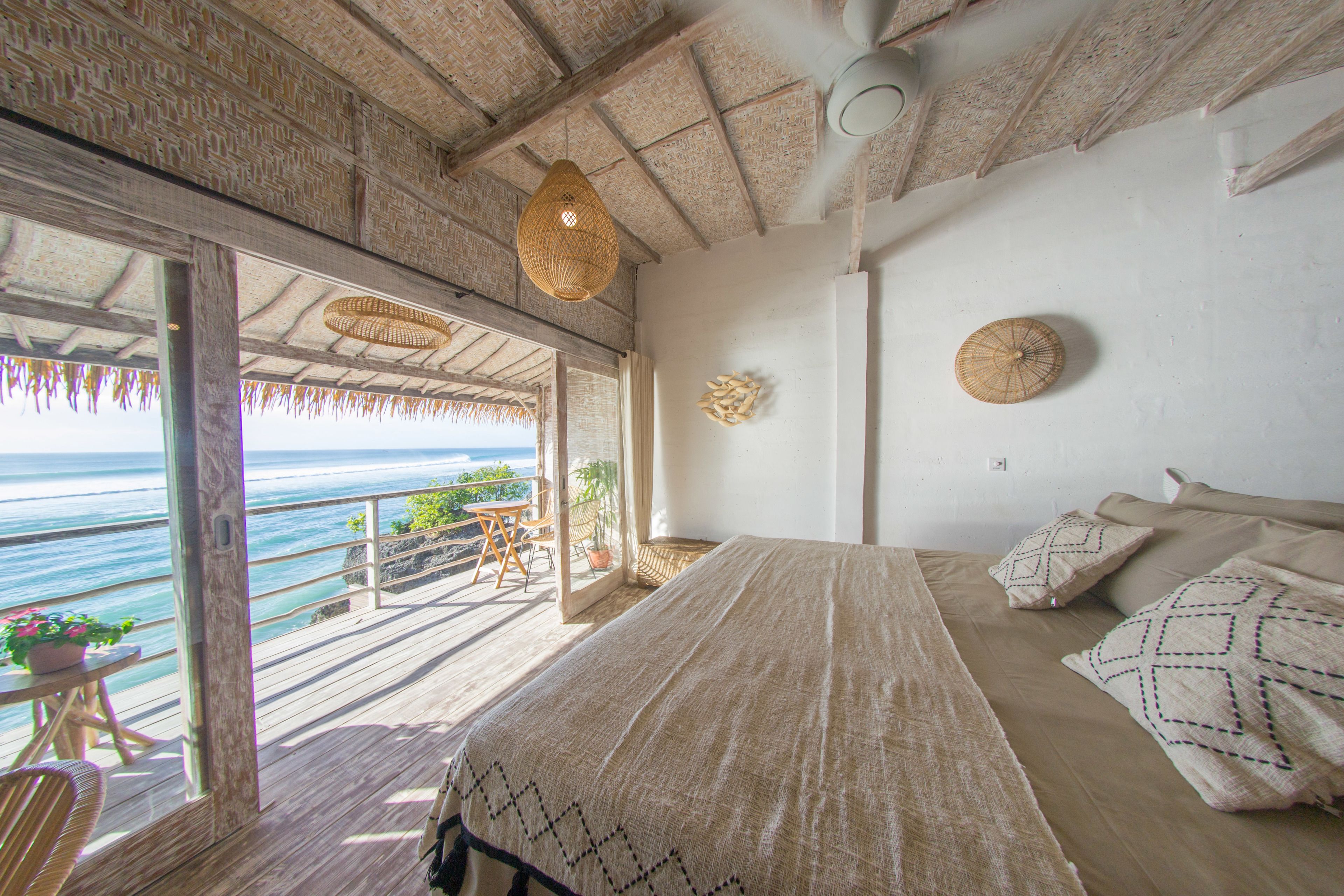 A bedroom with a large bed, a ceiling fan, and a view of the ocean.