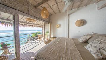 A bedroom with a large bed, a ceiling fan, and a view of the ocean.