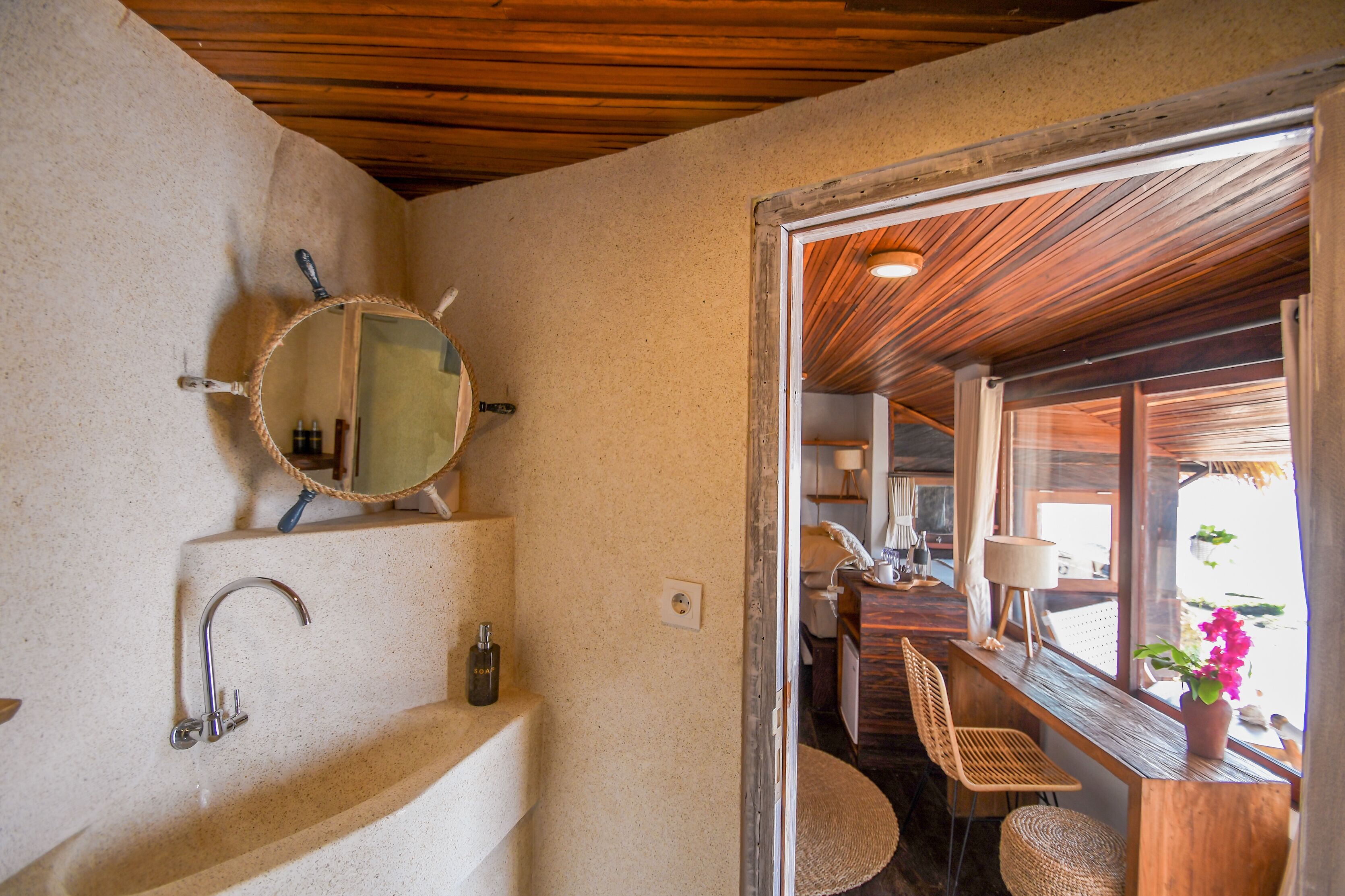 Une salle de bain avec un lavabo, un miroir et un plafond en bois.
