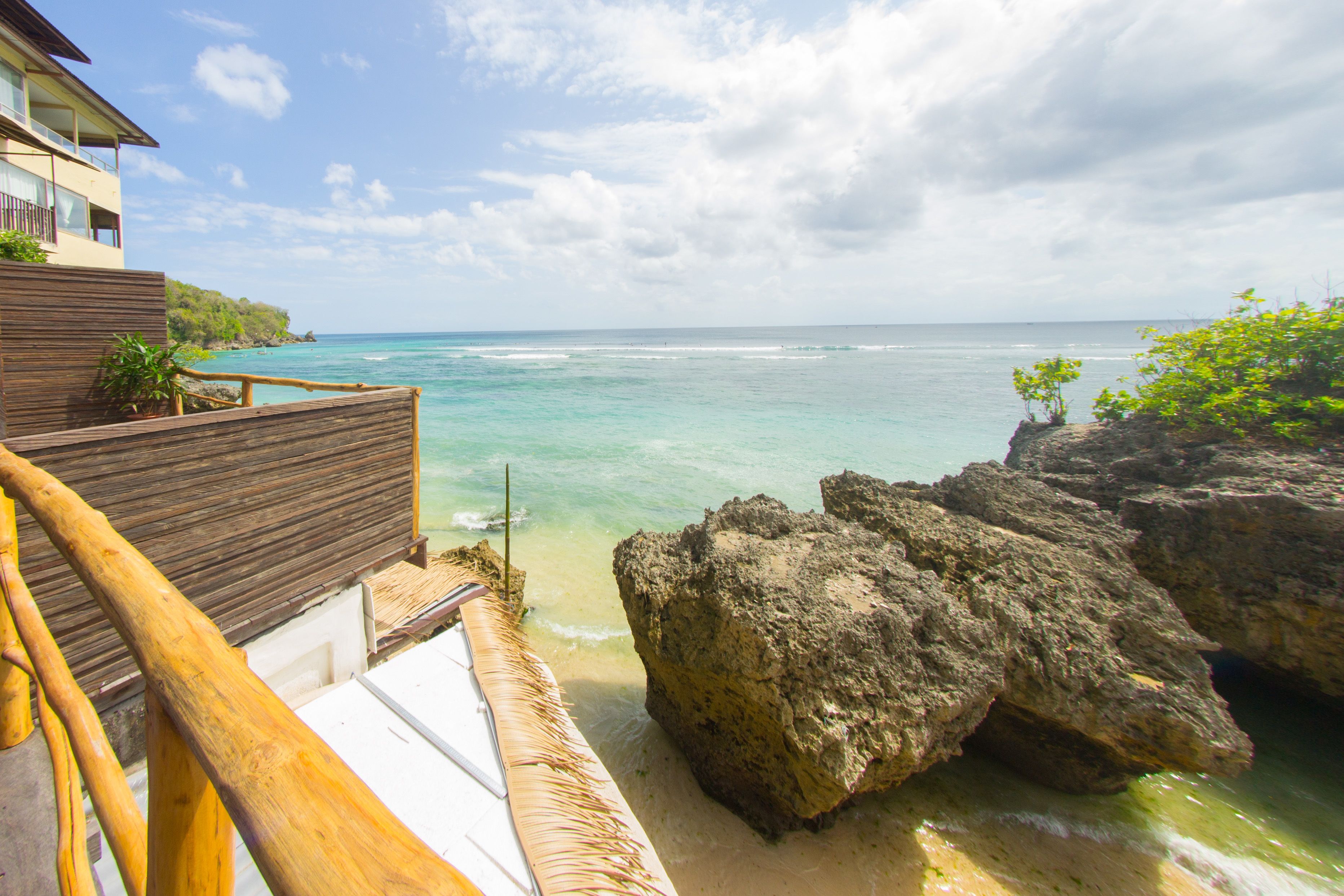 A wooden deck with a view of the ocean and a building with balconies.