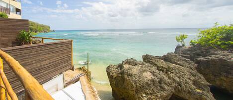 A wooden deck with a view of the ocean and a building with balconies.