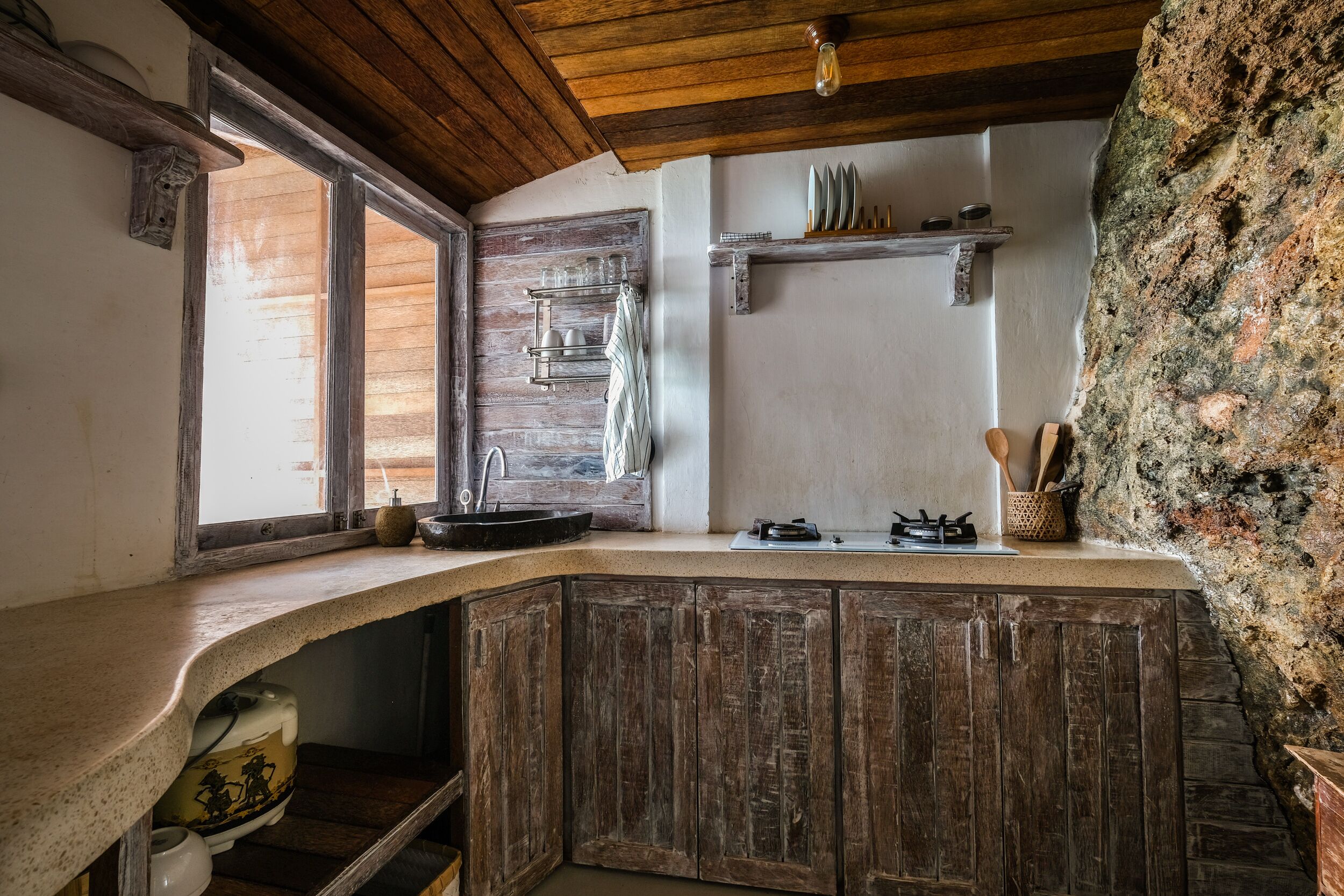 Une cuisine rustique avec des meubles en bois, un mur en pierre et une fenêtre offrant une belle vue.
