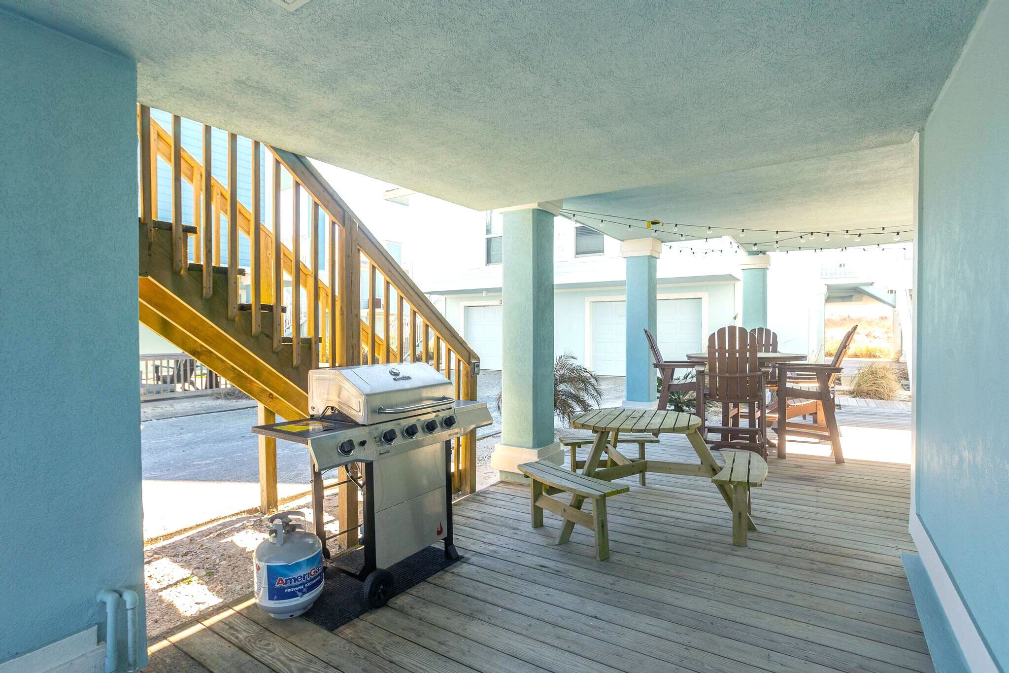 Une terrasse extérieure couverte, équipée d’un barbecue, d’une table de pique-nique et de chaises.
