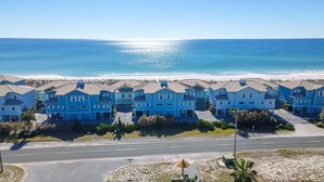 Zona residencial à beira-mar, com várias casas azuis, uma rua e uma praia ao fundo.