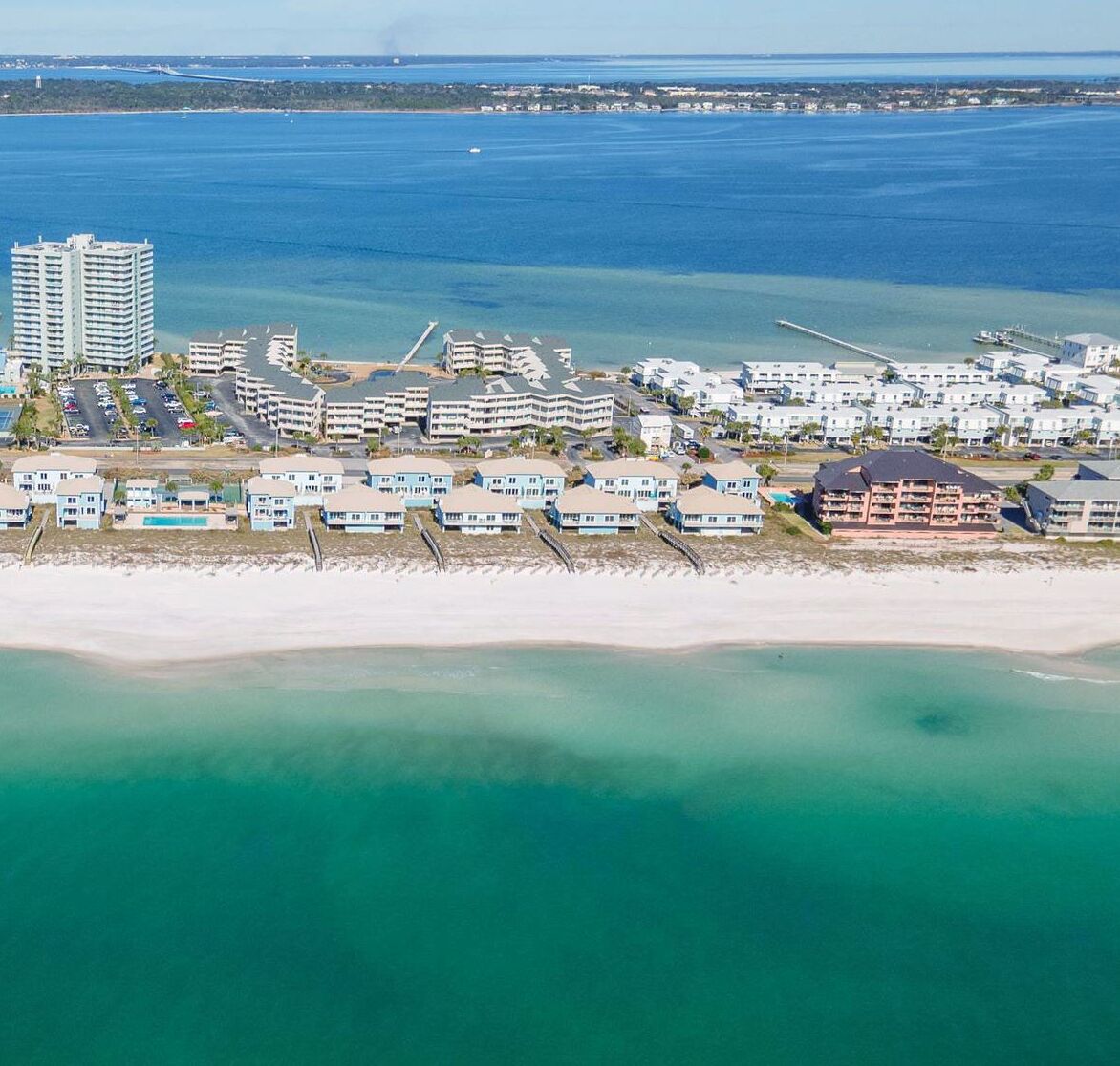 A coastal resort with beachfront villas, a marina, and a pier.