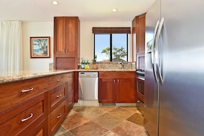 A kitchen with wooden cabinets, a stainless steel refrigerator, and a dishwasher. - Beautiful updated 2bd condo, a sleek new finish (Lahaina)