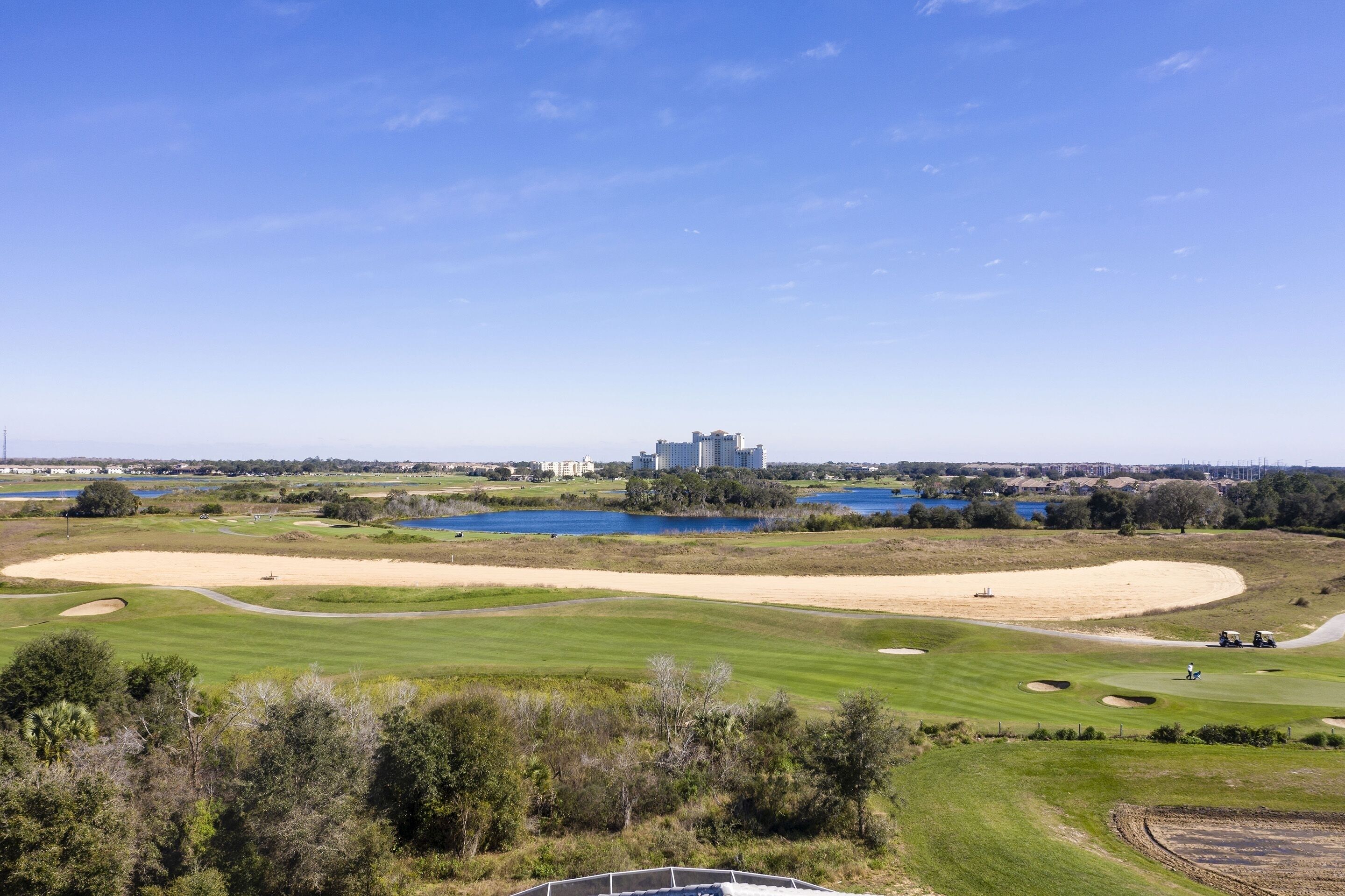 Un parcours de golf avec des bunkers, un plan d’eau et des bâtiments situés au loin.