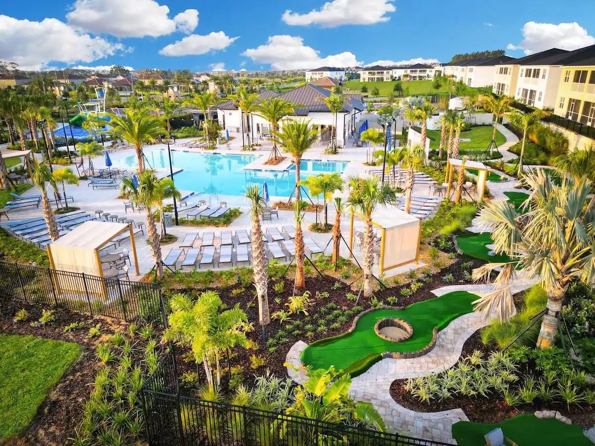 A resort with a swimming pool, palm trees, and a golf course.