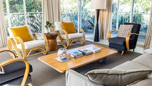 Una sala de estar moderna con sillas de mimbre, un sofá negro y una mesa de centro de madera.