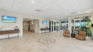 A spacious lobby with a reception desk, seating area, and large windows offering a view of the outdoors.