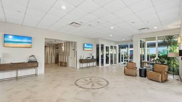 A spacious lobby with a reception desk, seating area, and large windows offering a view of the outdoors.