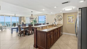 A spacious kitchen with a large island, a dining area with chairs, and a view of the ocean.