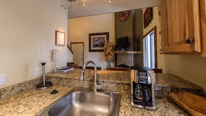 A kitchen with granite countertops, a stainless steel sink, a coffee maker, and a telephone. - Emmons Condo | 2 Bedroom plus Loft | Steps to Lifts | Shared Hot Tub | Parking (Mt. Crested Butte)