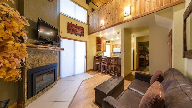 A cozy living room with a fireplace, a television, and a comfortable seating area. - Emmons Condo | 2 Bedroom plus Loft | Steps to Lifts | Shared Hot Tub | Parking (Mt. Crested Butte)