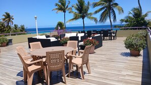 A rooftop patio with outdoor seating, a pool, and a view of the ocean.