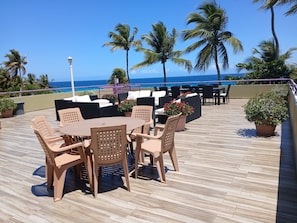 A rooftop patio with outdoor seating, a pool, and a view of the ocean.