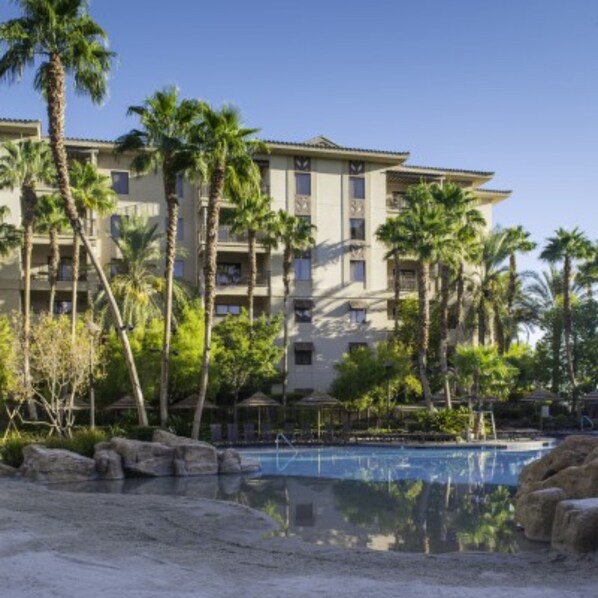 Ein Hotel mit mehreren Etagen, Palmen und einem Swimmingpool.