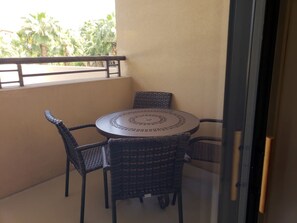 Ein kleiner Balkon mit einem runden Tisch und vier Korbstühlen.