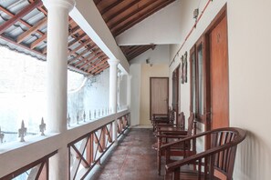 A corridor with a wooden ceiling, white columns, and a row of wooden chairs. - OYO 146 Menteng Residence Near Kementerian Perencanaan Pembangunan Nasional/Badan Perencanaan Pembangunan Nasional (Kementerian PPN/Bappenas) (Jakarta)