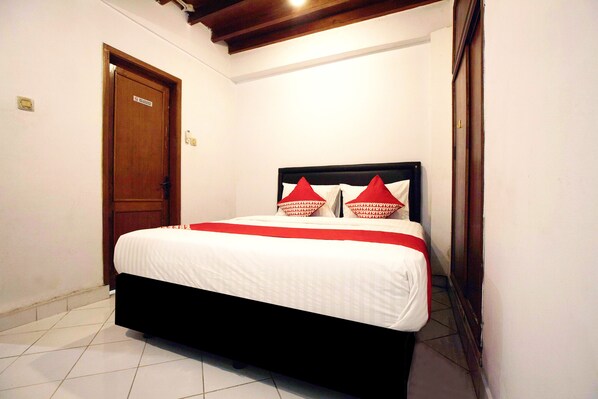 A bedroom with a bed, a wooden door, and a tiled floor. - OYO 146 Menteng Residence Near Kementerian Perencanaan Pembangunan Nasional/Badan Perencanaan Pembangunan Nasional (Kementerian PPN/Bappenas) (Jakarta)