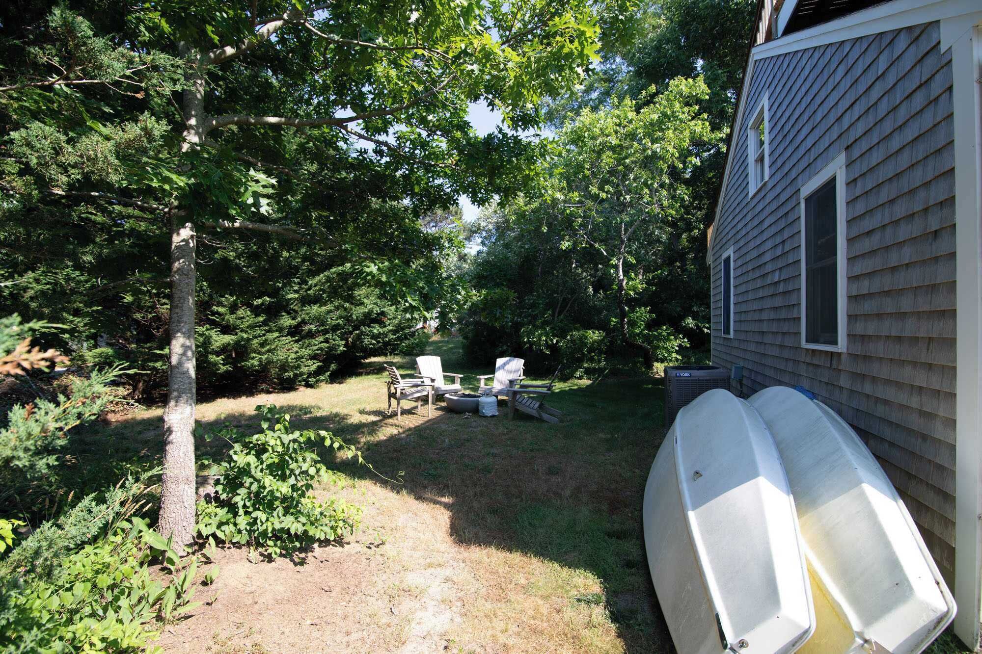 A backyard with a small deck, outdoor seating, and a house.