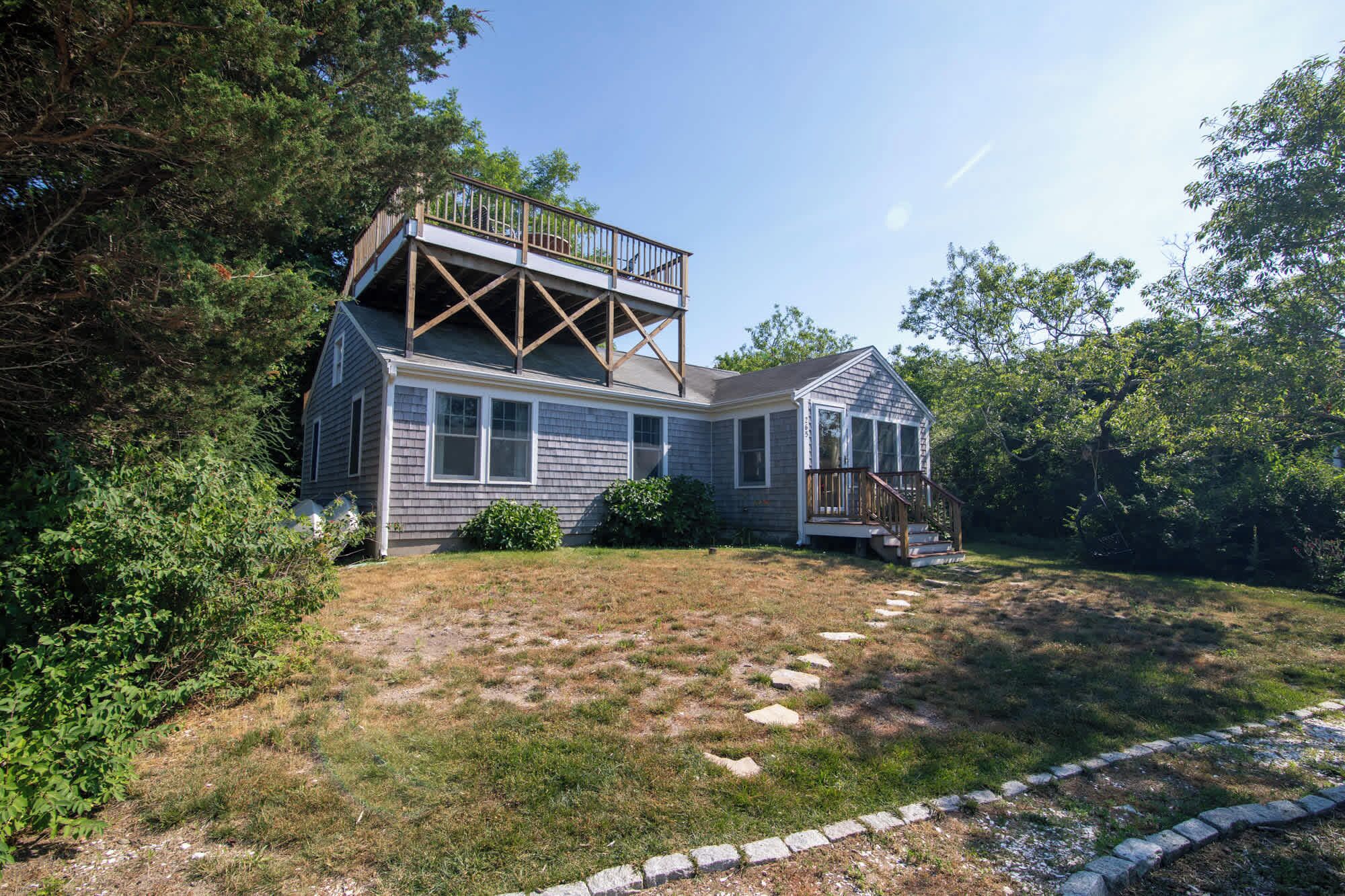 A two-story house with a deck and a covered porch.
