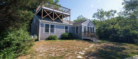 A two-story house with a deck and a covered porch.