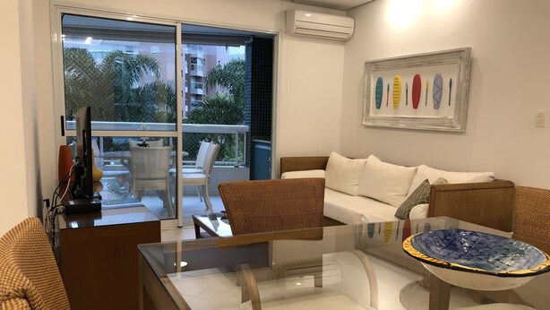 Ein modernes Wohnzimmer mit einem Glastisch, einer Couch und einem Essbereich mit Stühlen.