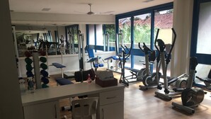 A gym with exercise equipment, a mirror, and a desk with a chair.