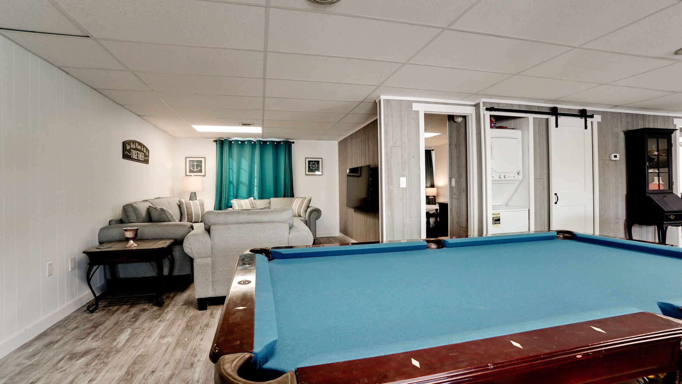 A pool table in a room with a sofa and a television.