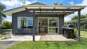 Une maison moderne dotée d’un patio couvert, d’un barbecue et d’une porte vitrée donnant sur l’intérieur.