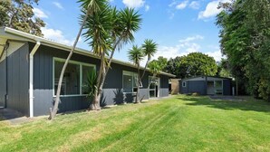 Une maison moderne à deux étages, dotée d’une pelouse bien entretenue et de palmiers.