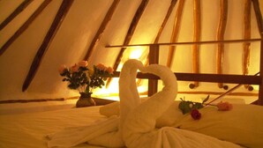 A bed with white towels arranged in a swan shape, a vase with flowers, and a wooden headboard in a cozy room. - The only and most charming luxury beachfront cottage on the Riviera Maya (Akumal)