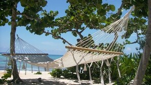 A hammock tied between trees on a sandy beach with clear blue water in the background. - The only and most charming luxury beachfront cottage on the Riviera Maya (Akumal)