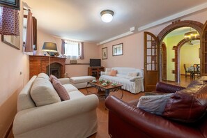 A living room with a fireplace, sofas, a coffee table, and an archway leading to another room.