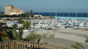 Un port esportiu amb nombroses embarcacions amarrades, un edifici alt i destacat, i una vista ampla del mar.