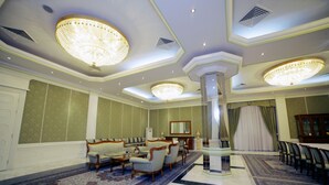 A spacious lobby with a high ceiling, ornate chandeliers, a central column, and a seating area with armchairs and a sofa. - Residence Park Hotel (Tashkent)