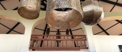 A ceiling with three hanging metallic lamps and a decorative wall panel below.