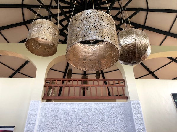 A ceiling with three hanging metallic lamps and a decorative wall panel below.