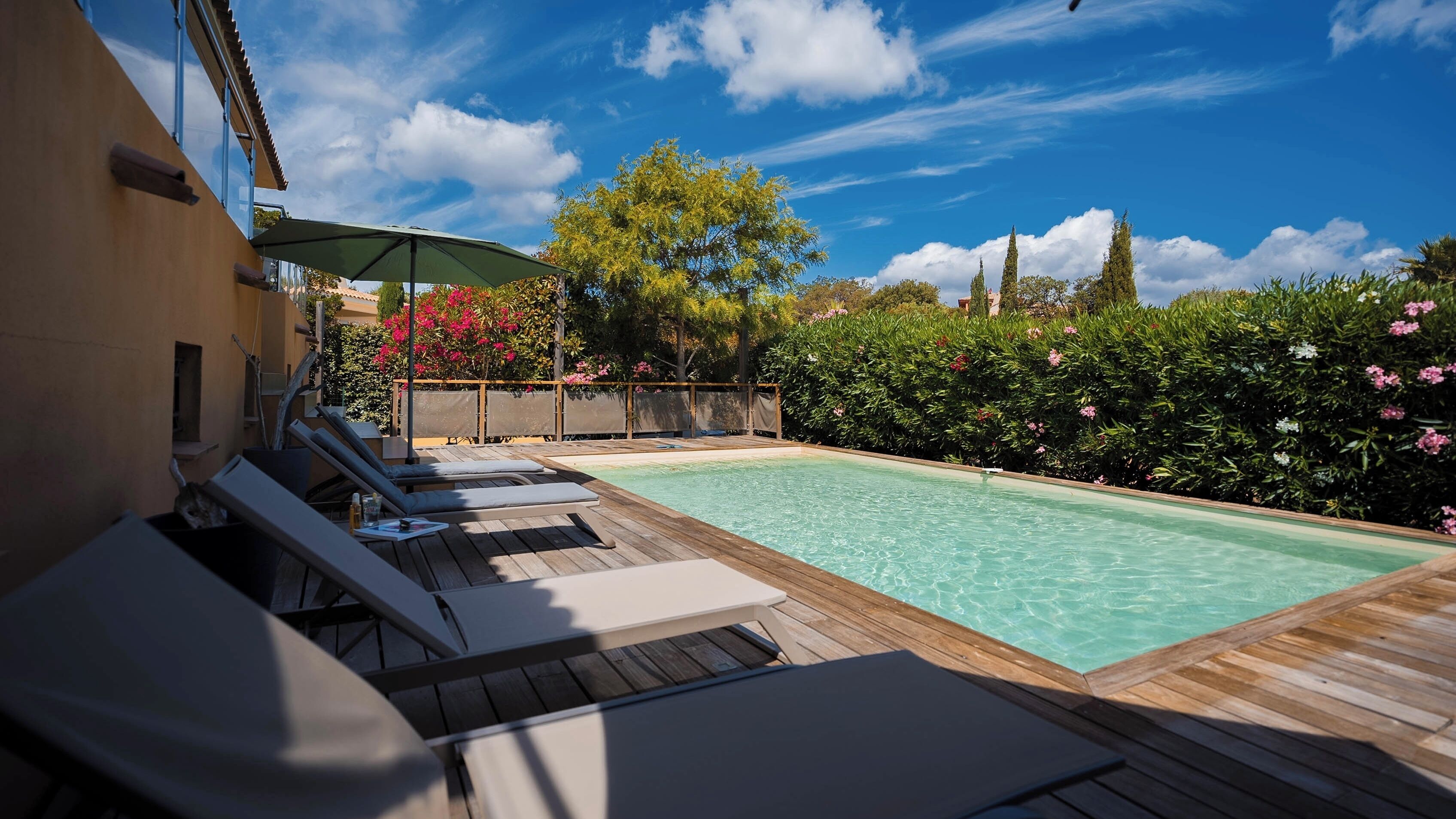 Une terrasse en bois avec des chaises longues et une piscine.