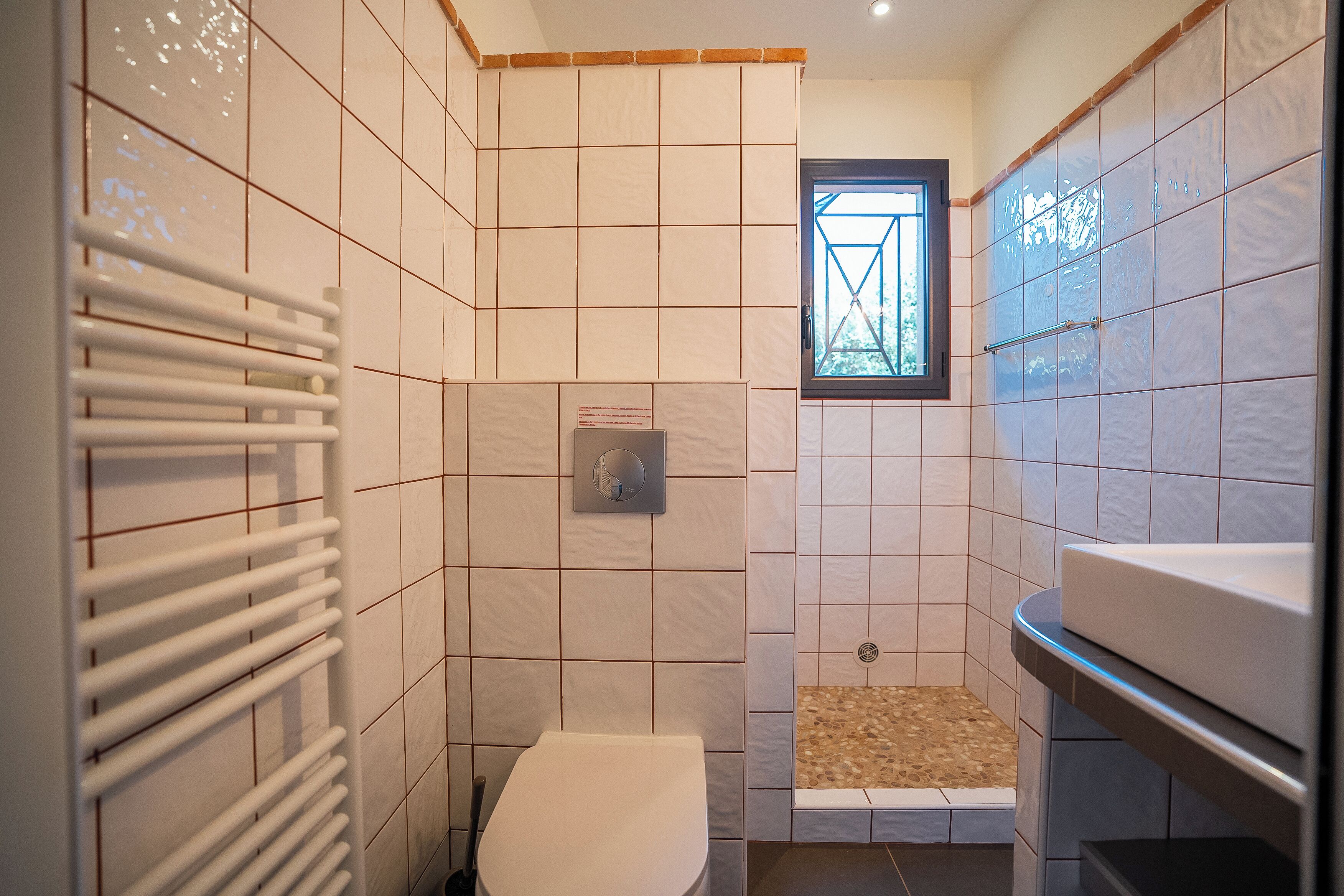 A compact bathroom with a toilet, a shower with a small window, and a towel rack.