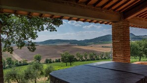 A covered outdoor seating area with a view of rolling hills and vineyards.