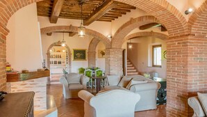 A spacious living area with a brick fireplace, a dining table with chairs, and a kitchen area with a wine rack.