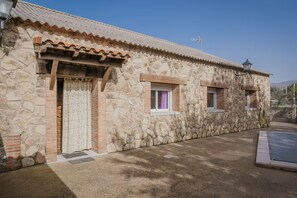 Un bâtiment en pierre avec un toit en tuiles, une porte en bois et deux fenêtres avec volets.