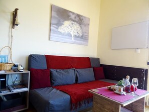 A cozy living room with a sofa, a table with a pink placemat, and a wall-mounted light fixture.