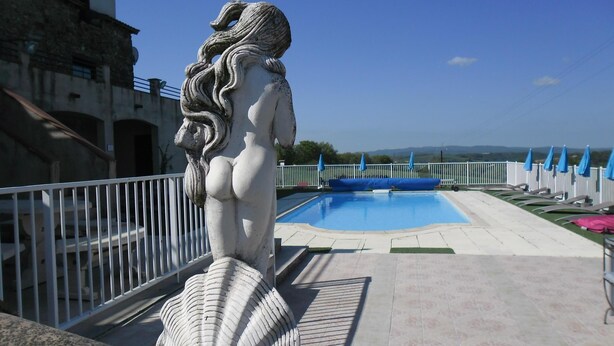 A statue of a woman by a pool with a view of the landscape.
