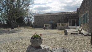 A courtyard with a building, a stone bench, and a potted plant.