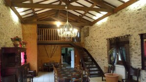 A rustic interior with a dining area, wooden furniture, a staircase, and a chandelier.