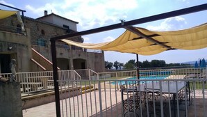 A pool area with a fenced patio, outdoor seating, and a building in the background.